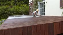 Frau streicht Terrasse mit Terrassenholzöl