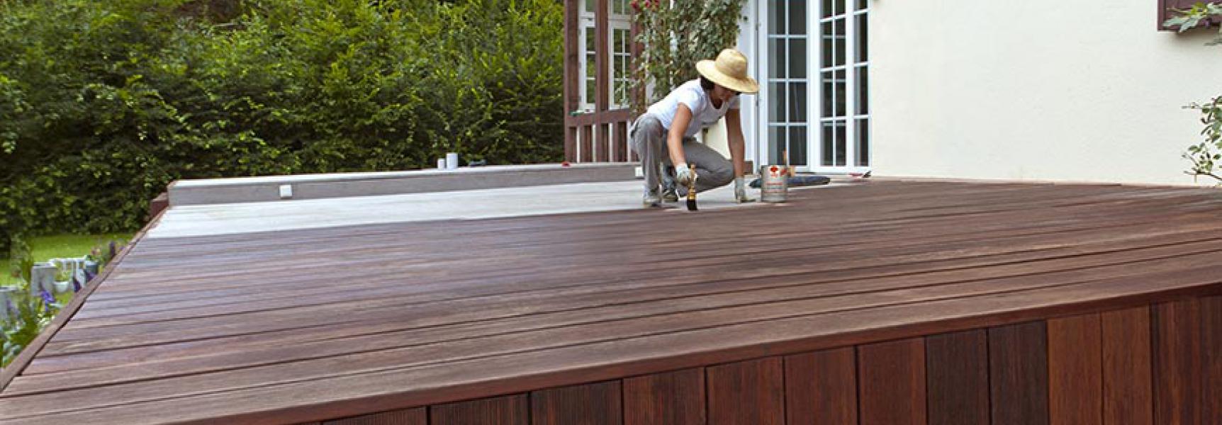 Frau streicht Terrasse mit Terrassenholzöl